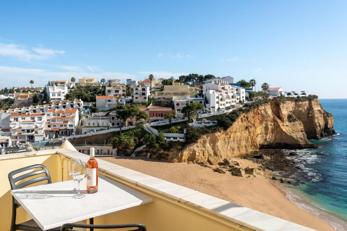 a small table and chair on a balcony overlooking Carvoeiro the best place to stay in Algarve for families