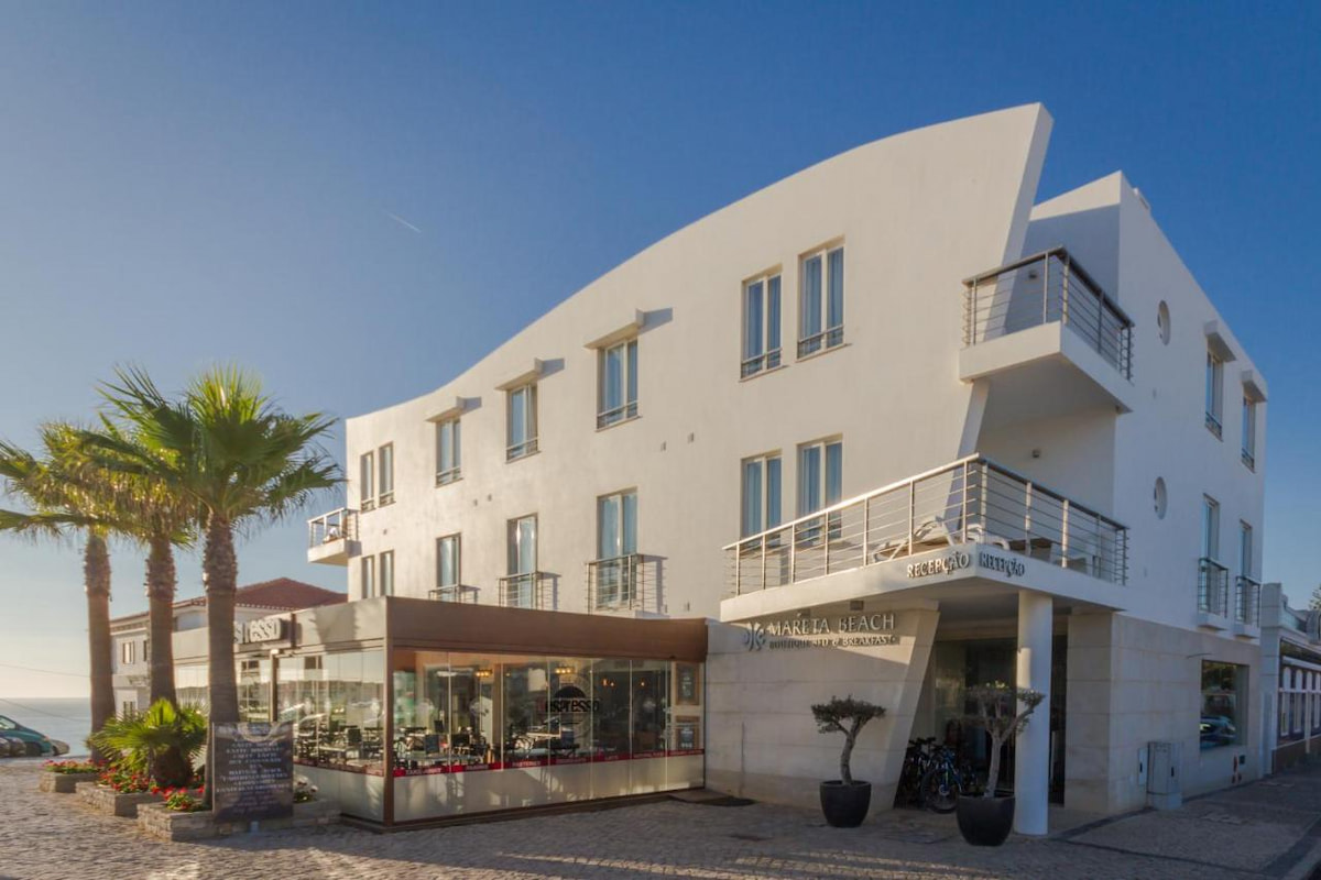 organically shaped boutique hotel in the Algarve town of Sagres with palm trees and blue sky
