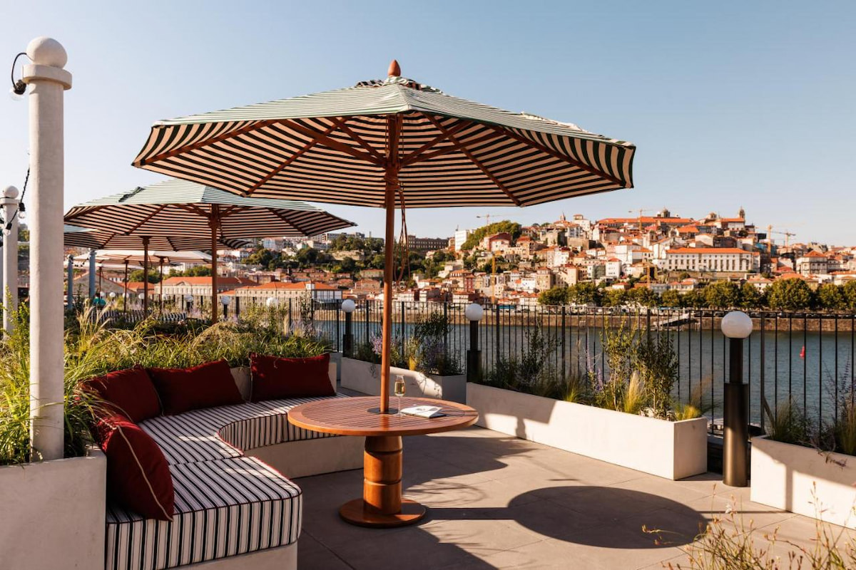 boutique hotel in Porto with outdoor furnishings and striped umbrella with Porto Portugal in the background on a sunny day