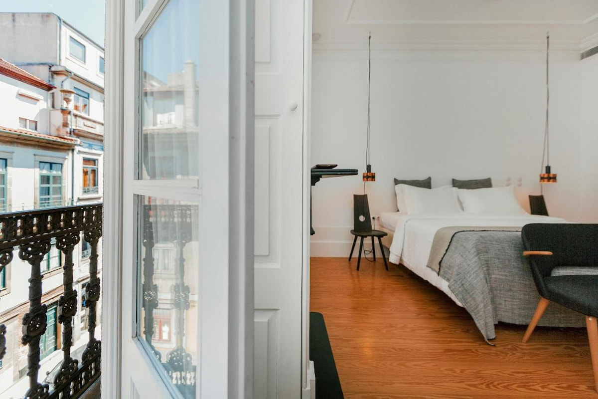 a hotel suite with wood floor opens up onto a balcony with city views of Cedofeita neighbourhood in Porto
