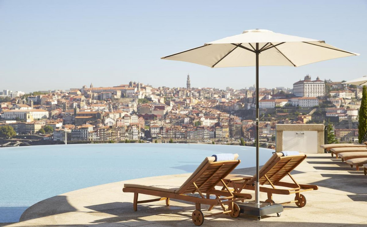 infinity pool overlooking Porto neighbourhoods with two sun loungers and white umbrella