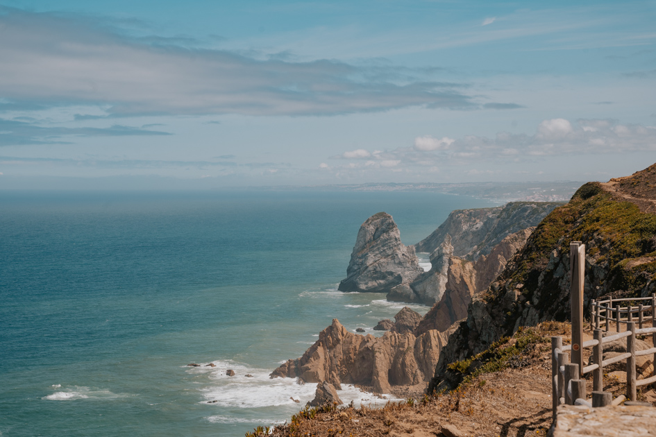 a rugged coastline with vast Atlantic Ocean on a cloudy and blue day at Cabo da Roca