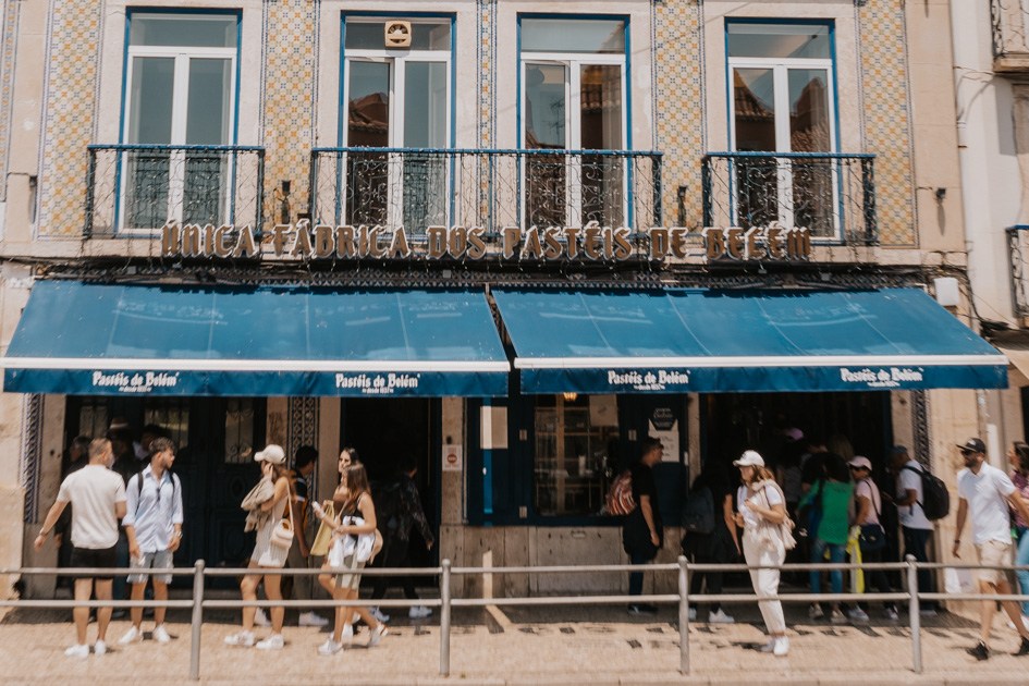 tourists walk outside of a historic pastel de nada shop with blue awning in Belem, Lisbon what to do