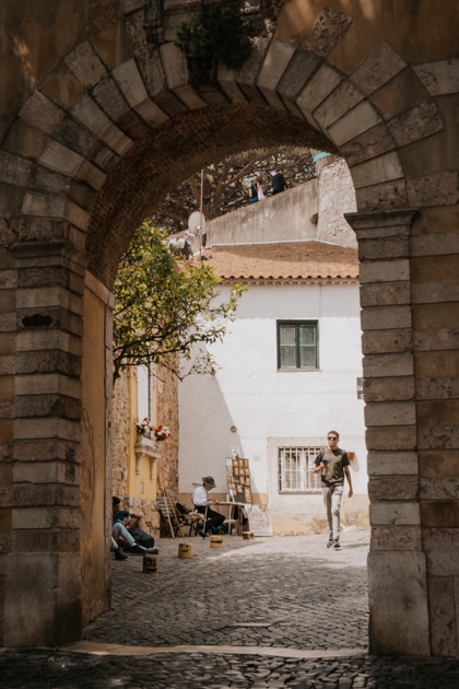 a dark stone curved arch leading up to Sao Jorge Castle in Alfama, Lisbon, Portugal