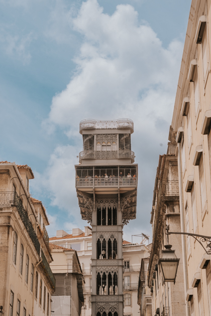 historic Santa Justa Lift elevator stands amongst beige buildings in Baixa Lisbon