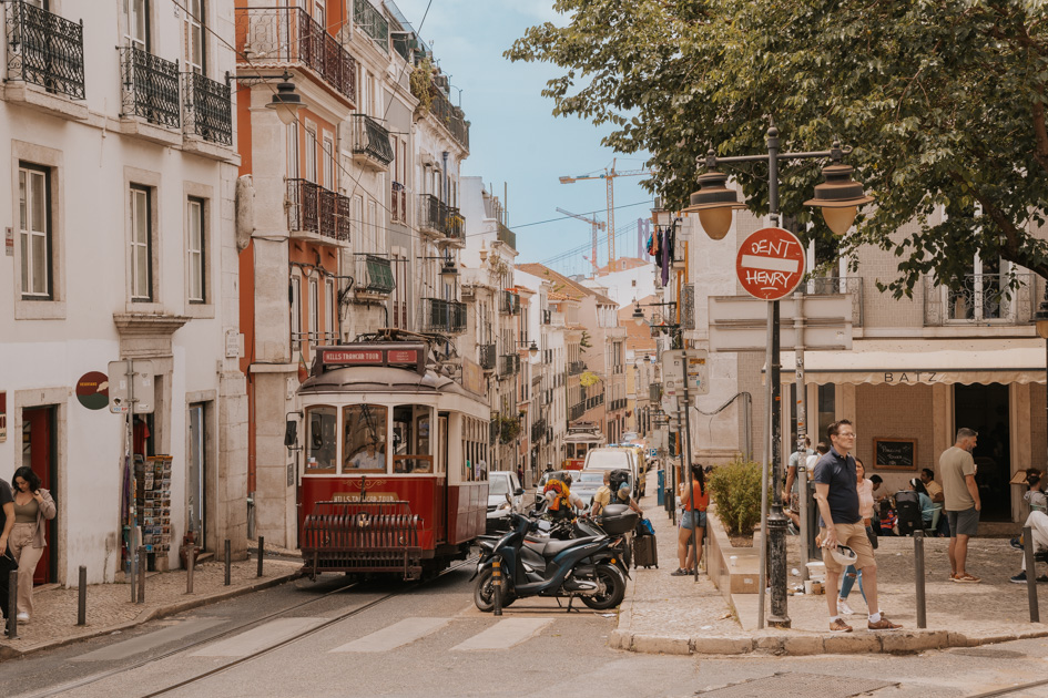 a historic red tram runs along the bustling streets of Lisbon travel guide