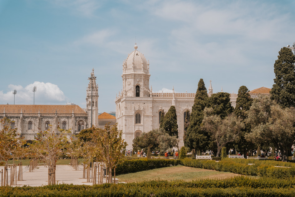 Late gothic monastery stands beyond a green landscape on a sunny day in Lisbon Portugal