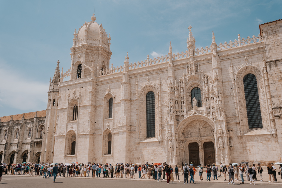 a queue of tourists in front of the gothic white stone Jeronimos Monastery on a clear blue day in Lisbon for 1 day