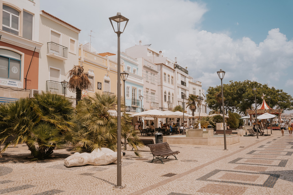 tiled promenade lined with lamp posts and colourful homes with greenery line one of the best places to stay in Algarve for first time visitors Lagos