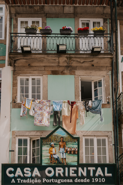three story historical Portuguese townhouse with laundry hanging and sign that reads 'casa oriental' 