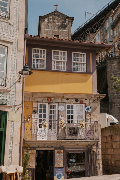yellow townhouse with white windows wedged between buildings in Porto's neighbourhood of Baixa