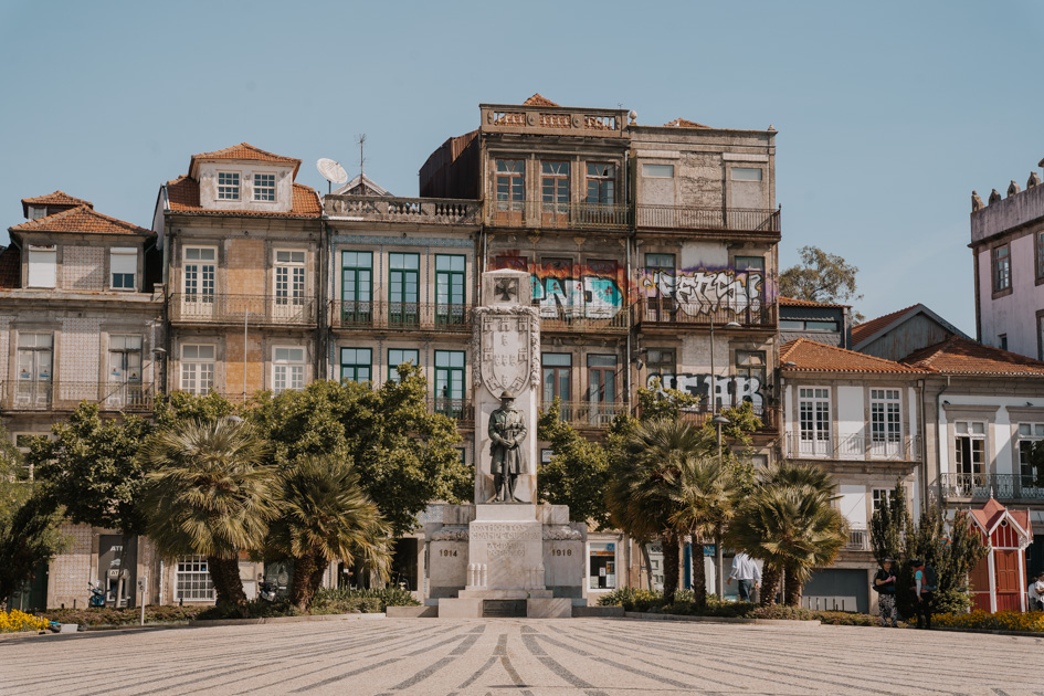gritty historical buildings line a green square with iron statue in Porto's Cedofeita neighbourhood which is the coolest place to stay in Porto