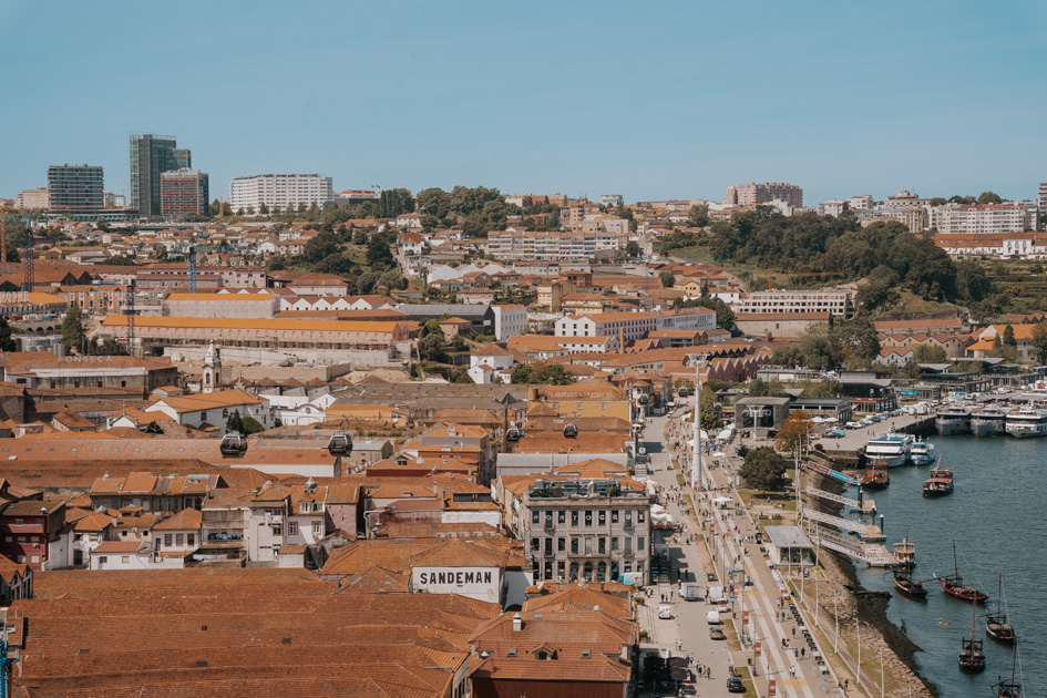 overlooking the district of Vila Nova de Gaia on the south bank of Porto with red tiled roofed buildings along a riverfront on a sunny day