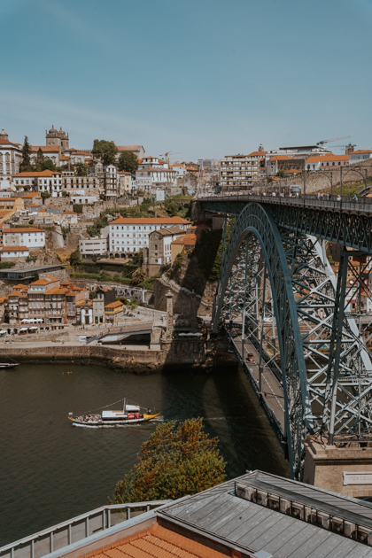 views over a river with boat and steel bridge from Vila Nova de Gaia neighbourhood in Porto Portugal