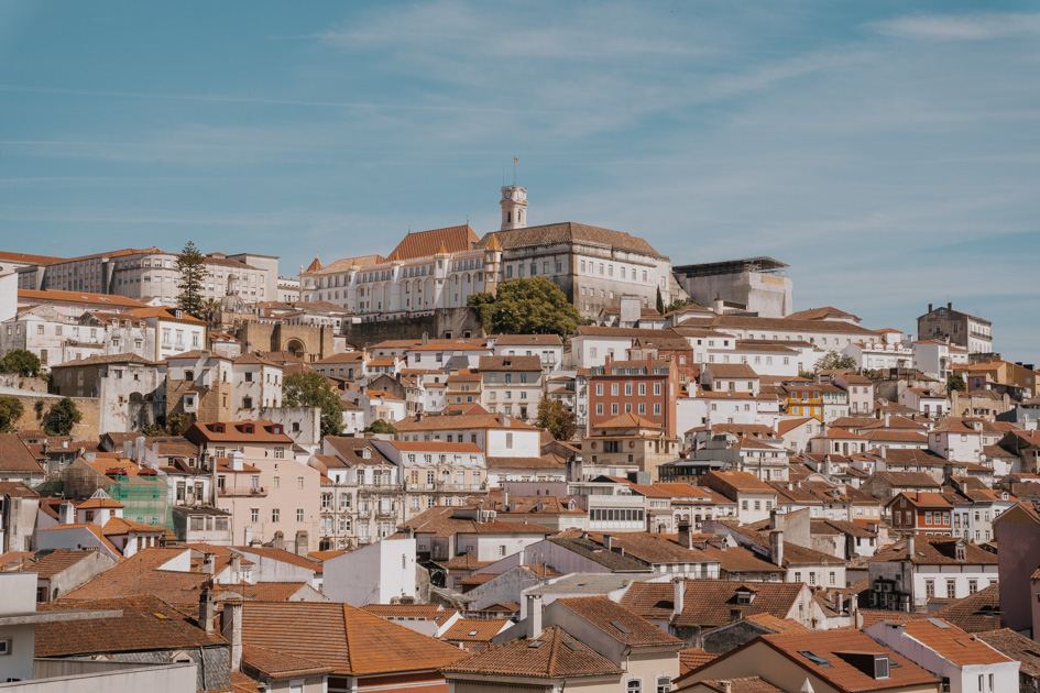 traditional Portguese white buildings with tiled red roofs line a hill in Coimbra where to stay on the Silver Coast of Portugal for history lovers