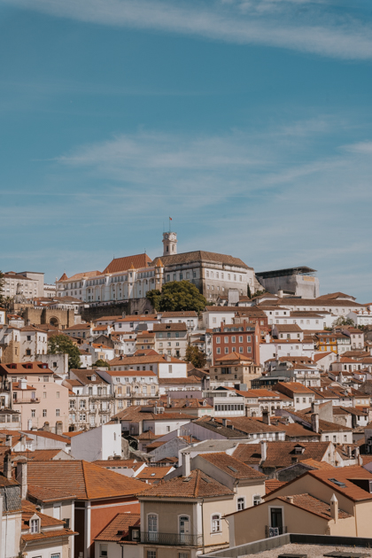 Panoramic of Coimbra with white buildings and red tiled roofs on a partly cloudy day in one of Portugal Silver Coast's best towns